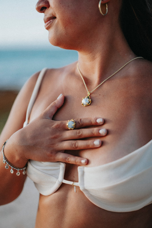 A girl wears a gold moonstone ring and a gold pearl pendant
