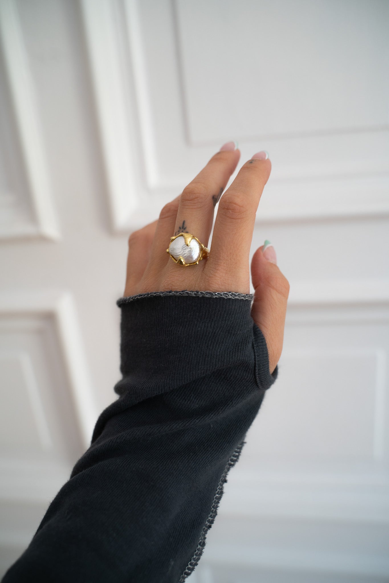 Hand with a golden pearl ring.